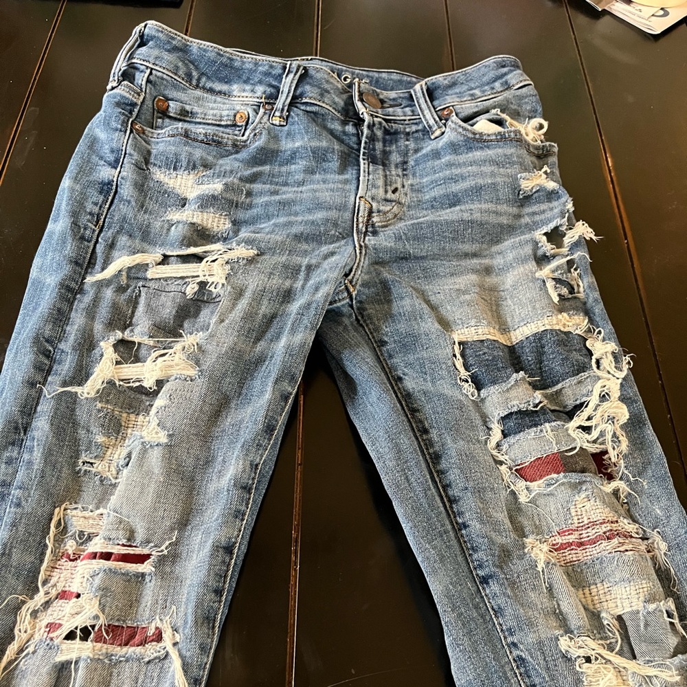 Men’s American eagle Airflex plus. Ripped denim with buffalo plaid patches.